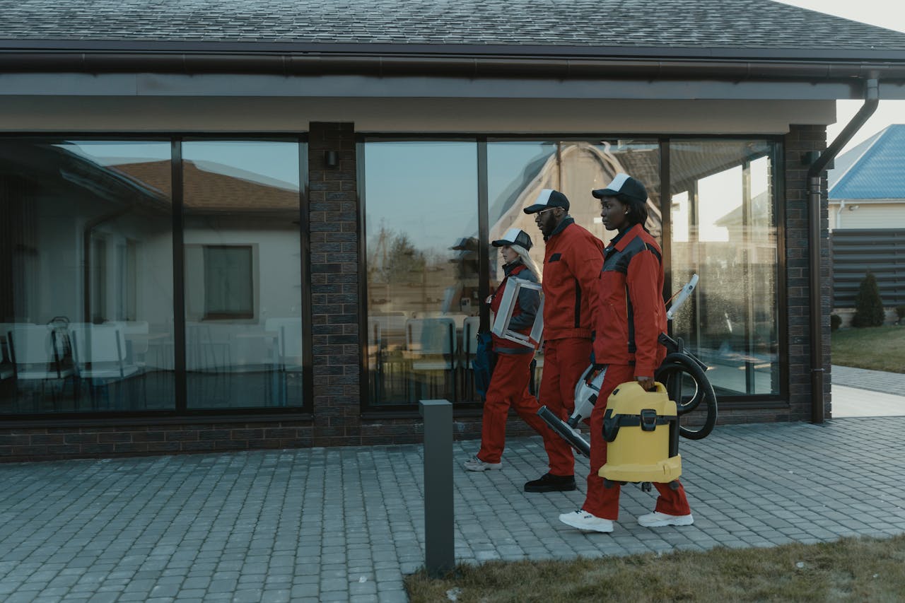 Three workers in uniform carrying cleaning supplies.